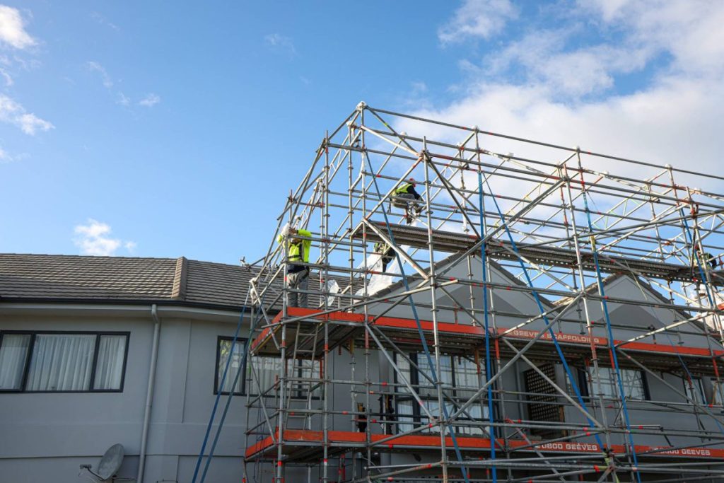 Workers on scaffolding set up alongside a house
