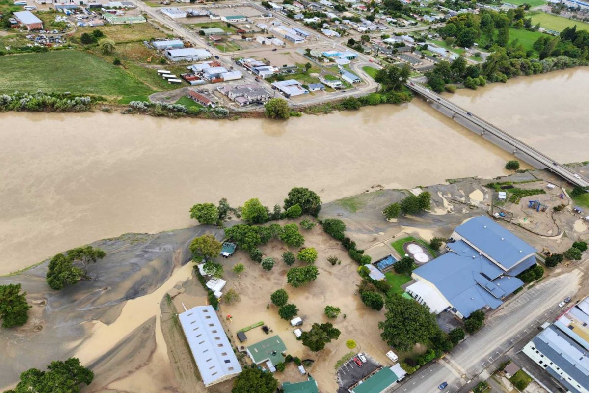 Aerial view of muddy river overflowing into nearby buildings and land